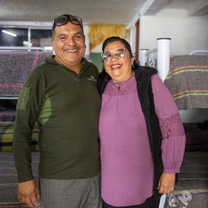 A man and woman smiling for a photo in front of a room of bunk beds