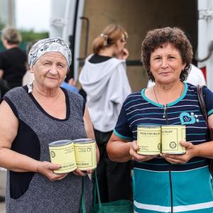 Two ladies holding canned meat
