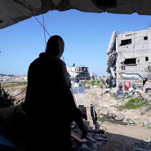 Woman looks out at destruction in front of her house.