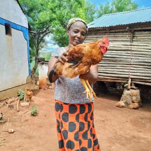 A woman smiling holding a chicken