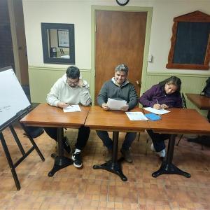 A group of three people sitting at a table signing some paperwork.