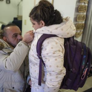 Man buttoning up his daughter's coat