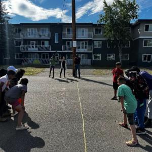 A group of children playing a game in front of an apartment complex