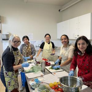 A group of women in a kitchen smiling for a photo