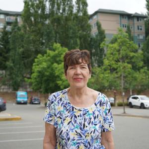 A woman standing in front of apartments smiling for a photo