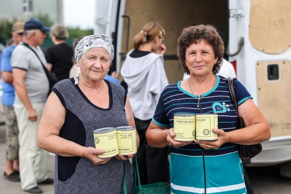 Two ladies holding canned meat