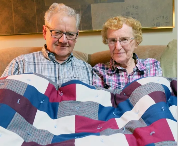 Harold and Miriam Tieszen holding a comforter they made to donate to beneficiaries through MCC. 