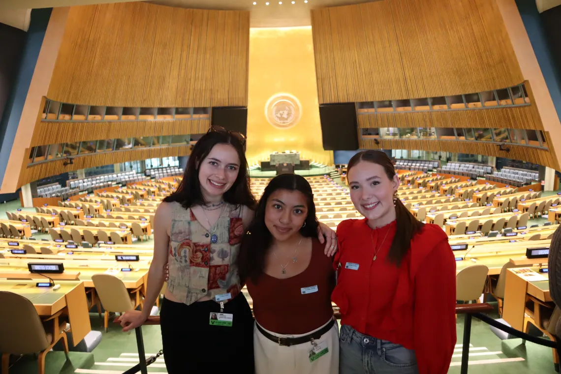 Three students pose inside the UN General Assembly Chamber. 