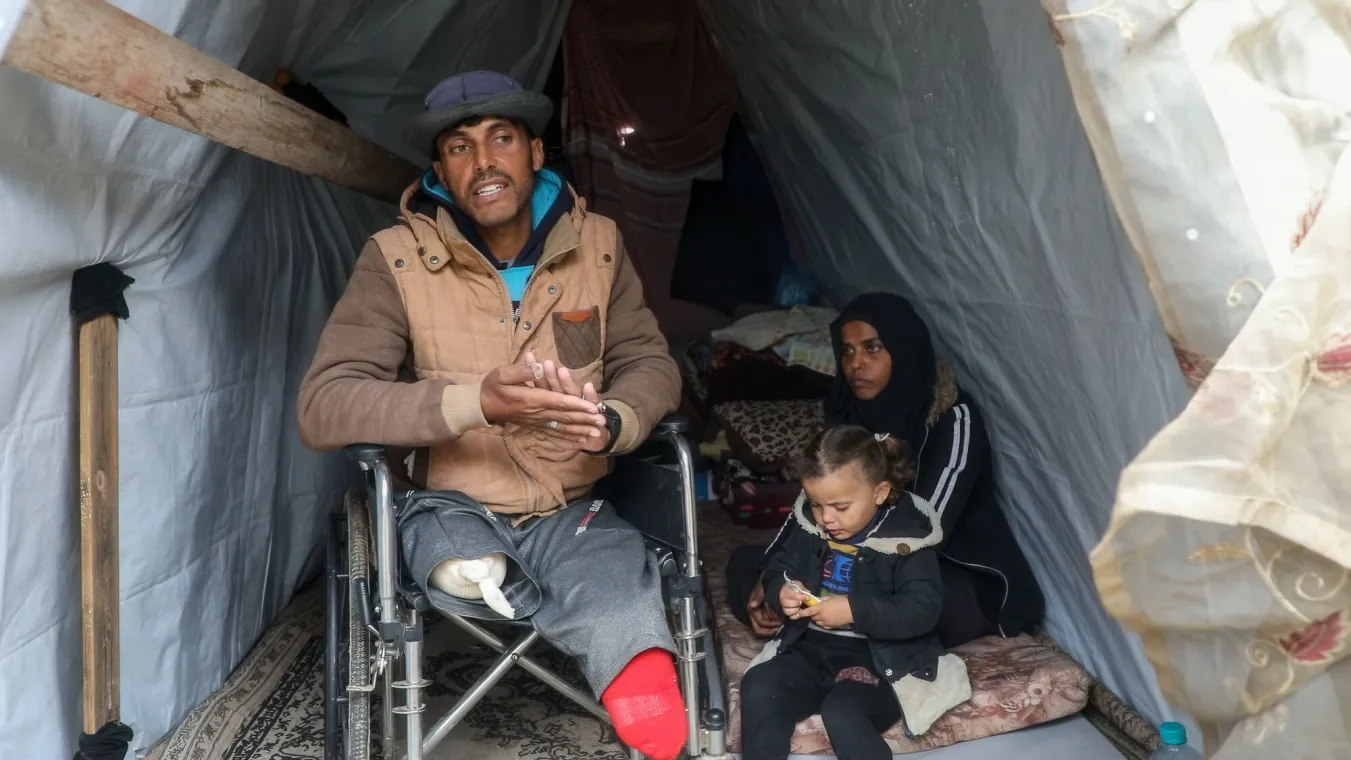 man with one leg in wheelchair beside daughter and wife sitting on the floor