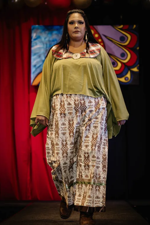 A woman models a vibrant two piece Indigenous designed outfit.