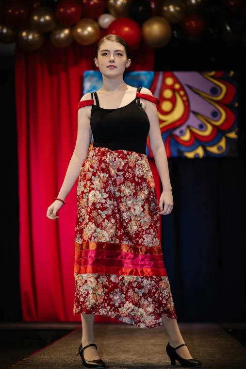 A young woman models a vibrant Indigenous designed outfit.