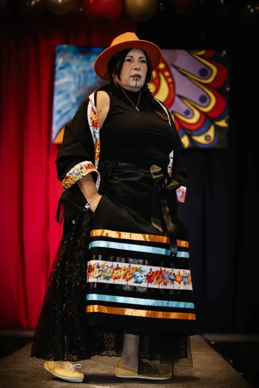 A woman models a vibrant, Indigenous-designed outfit.