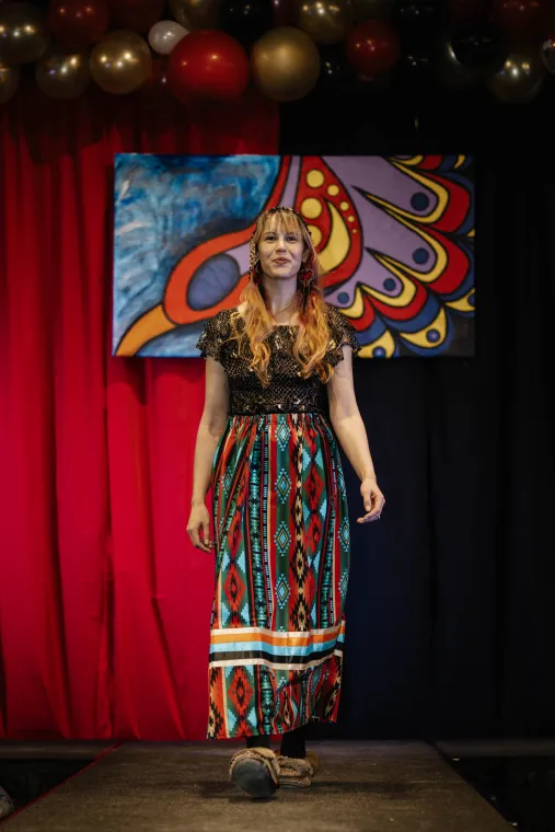 A woman models a vibrant ribbons skirt designed by an Indigenous artisan.