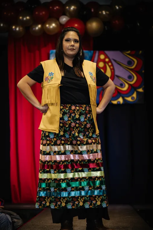 A woman models a beaded vest and skirt designed by an Indigenous artisan.