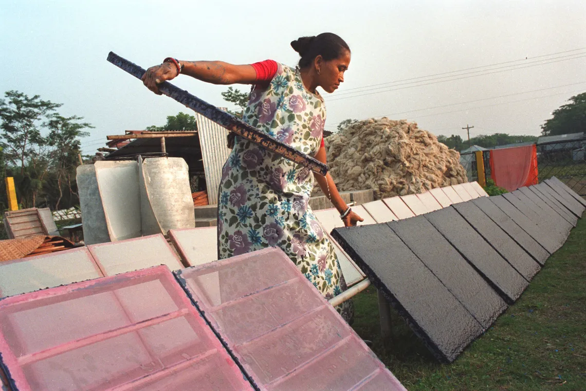 A woman adjusts panels of drying paper.