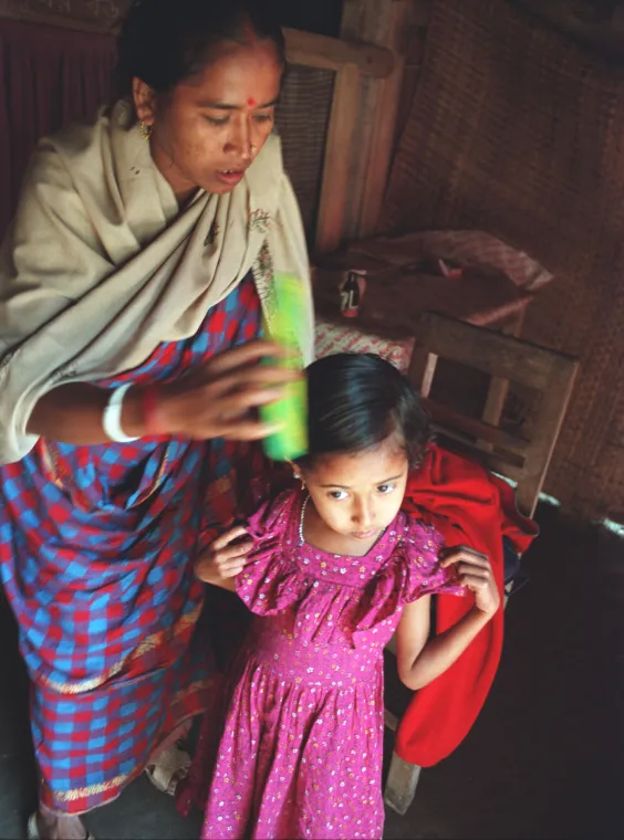 A woman combs her young daughter's hair.