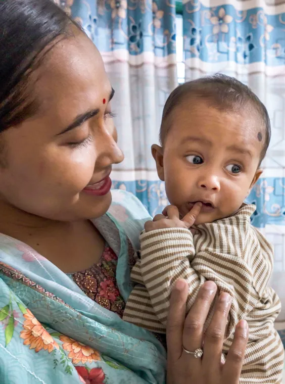 A woman looks at the baby she's holding with an affectionate smile.
