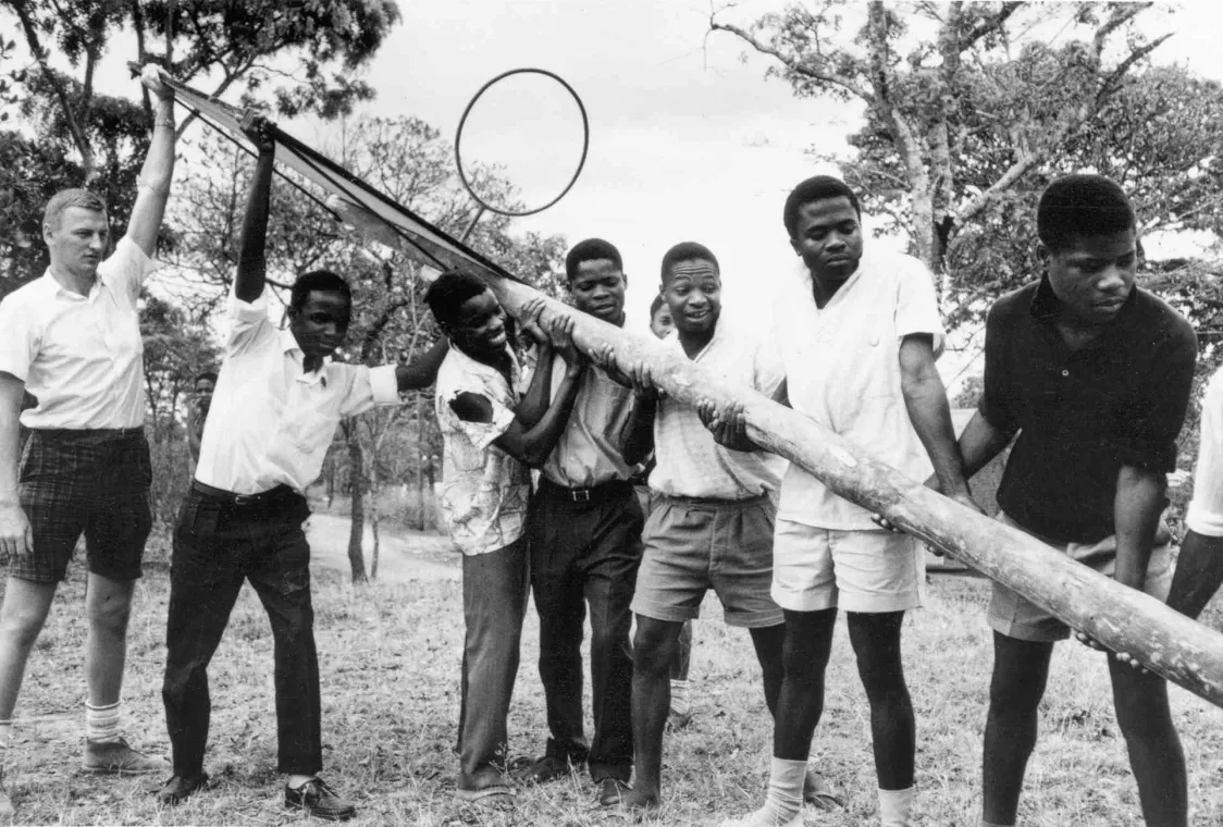 Group of young men holding a basketball pole.