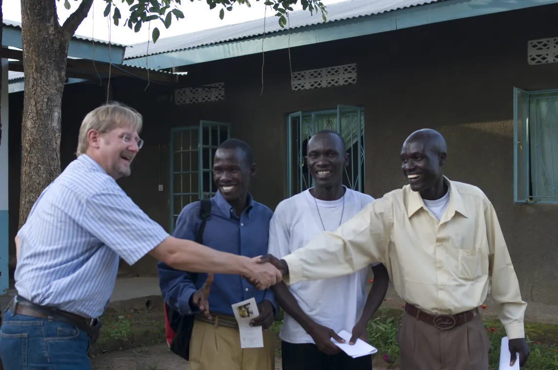 Four men, with two men shaking hands