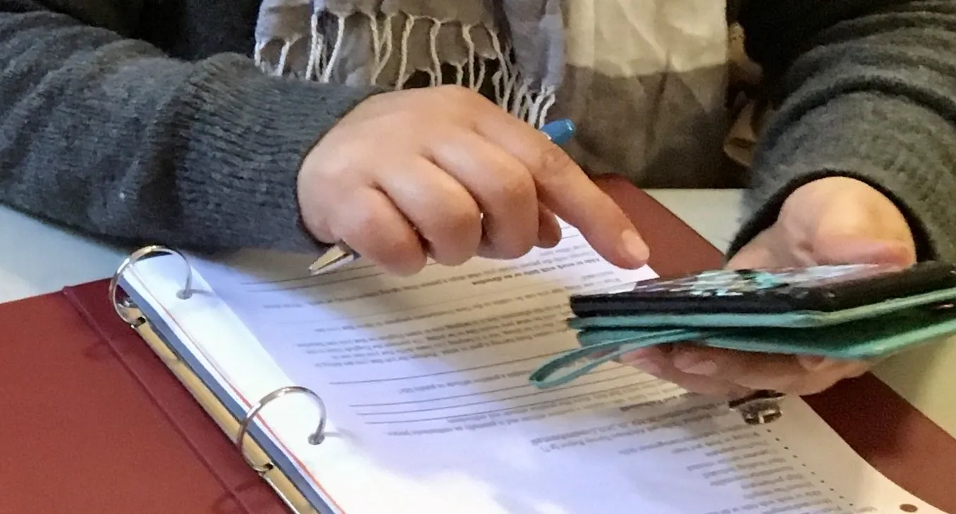 A pair of hands uses a phone as a calculator