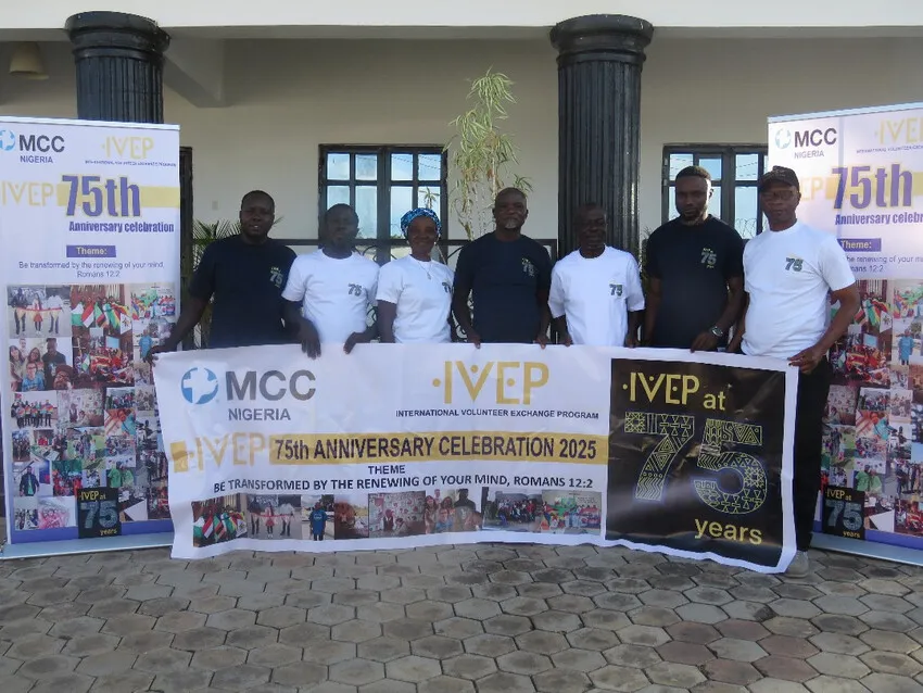 A group of seven people standing with IVEP banners celebrating the 75th anniversary in Nigeria