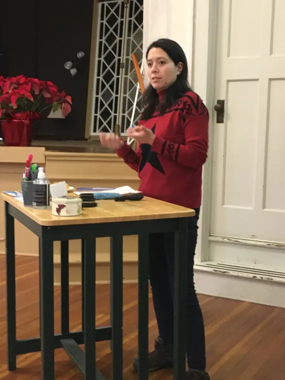 A woman stands behind a podium to facilitate a workshop