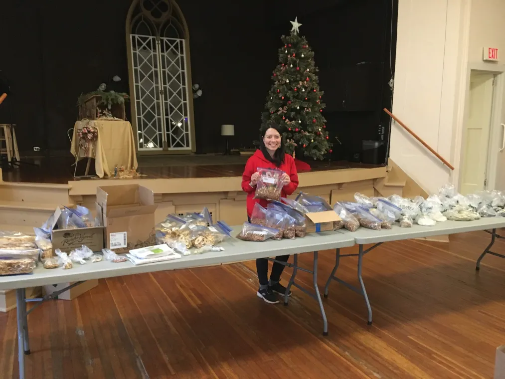 A woman stands behind a table filled with dry foods