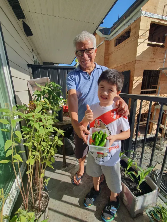 A grandfather and grandson holding plants on a patio garden