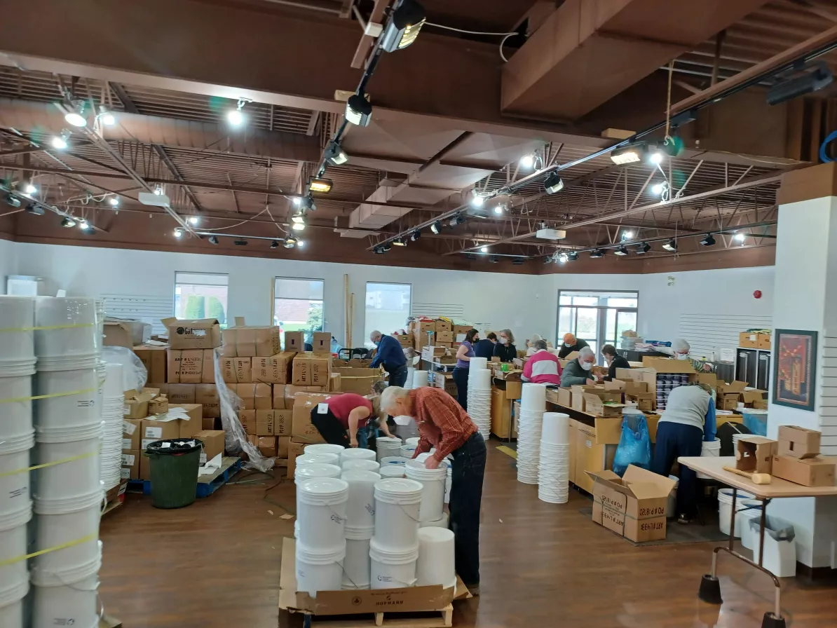 People working in a warehouse space filled with buckets and boxes