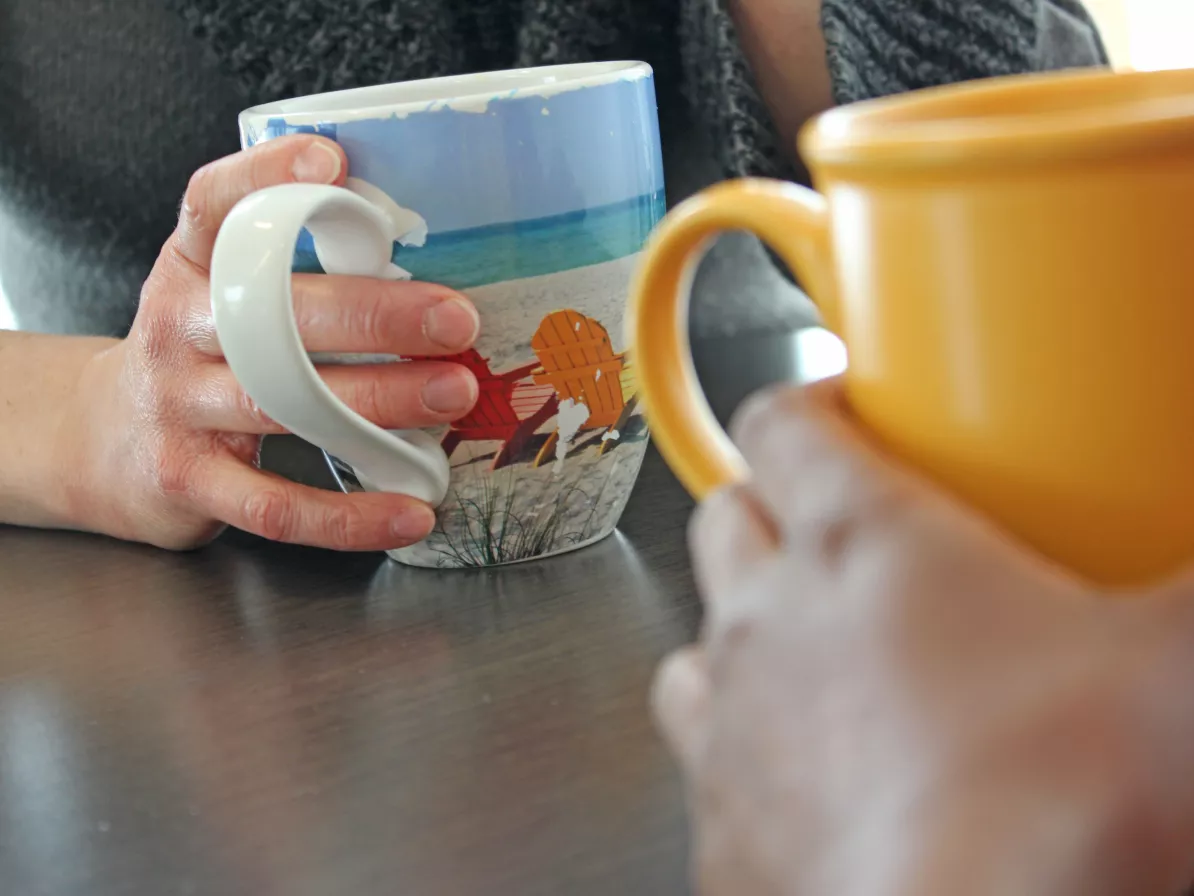 A close up of two people's hands holding coffee mugs