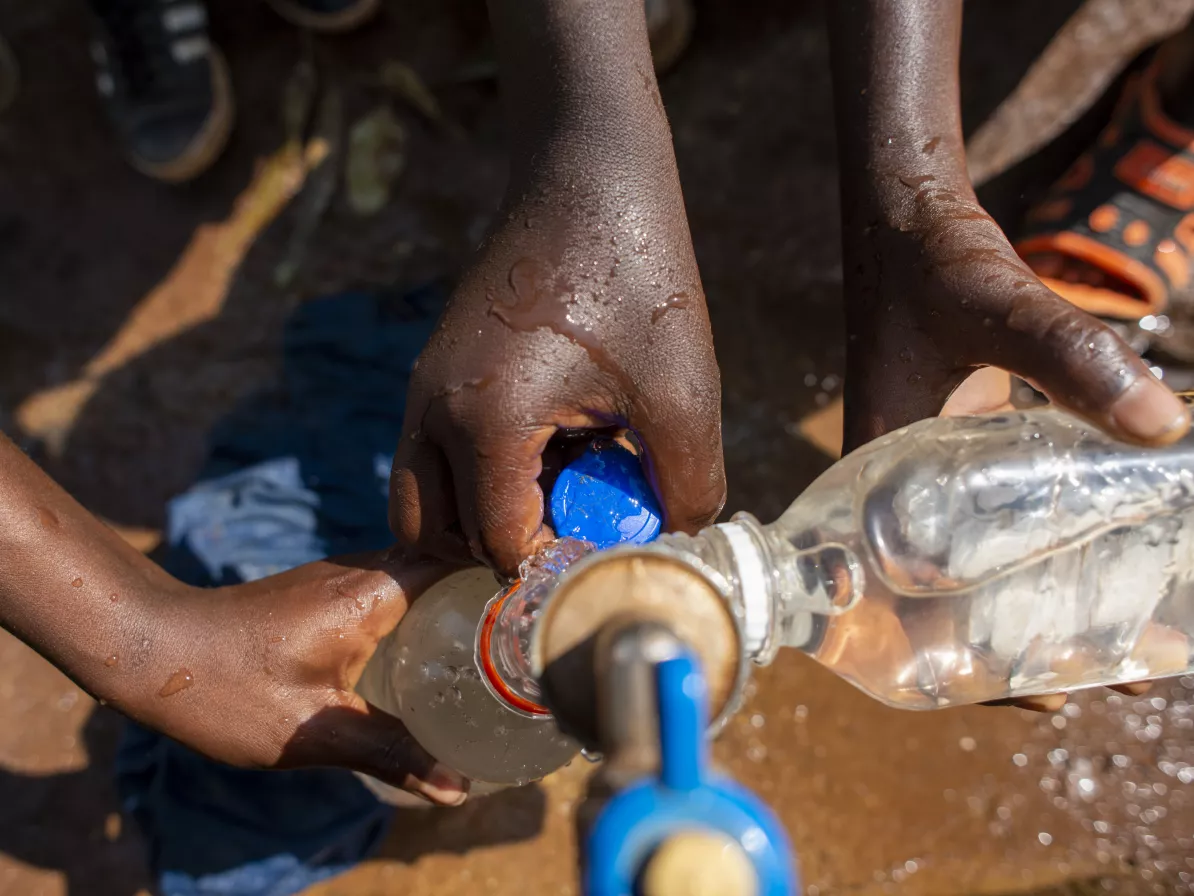 Children at Mosho II Primary School, in eastern Democratic Republic of the Congo, fill water containers with rain water collected from the rooftop catchment system at the school.