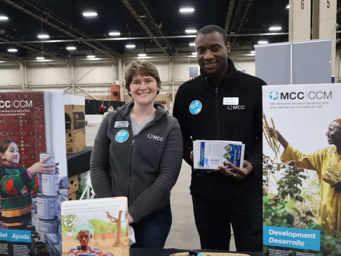 A man and woman standing at an MCC booth
