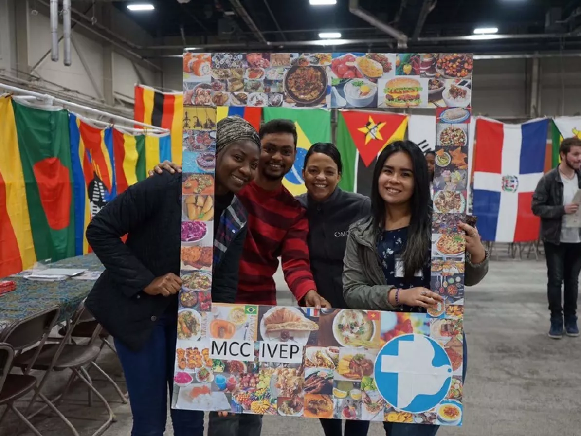 Four young adults pose for a photo behind a large, home made photo frame