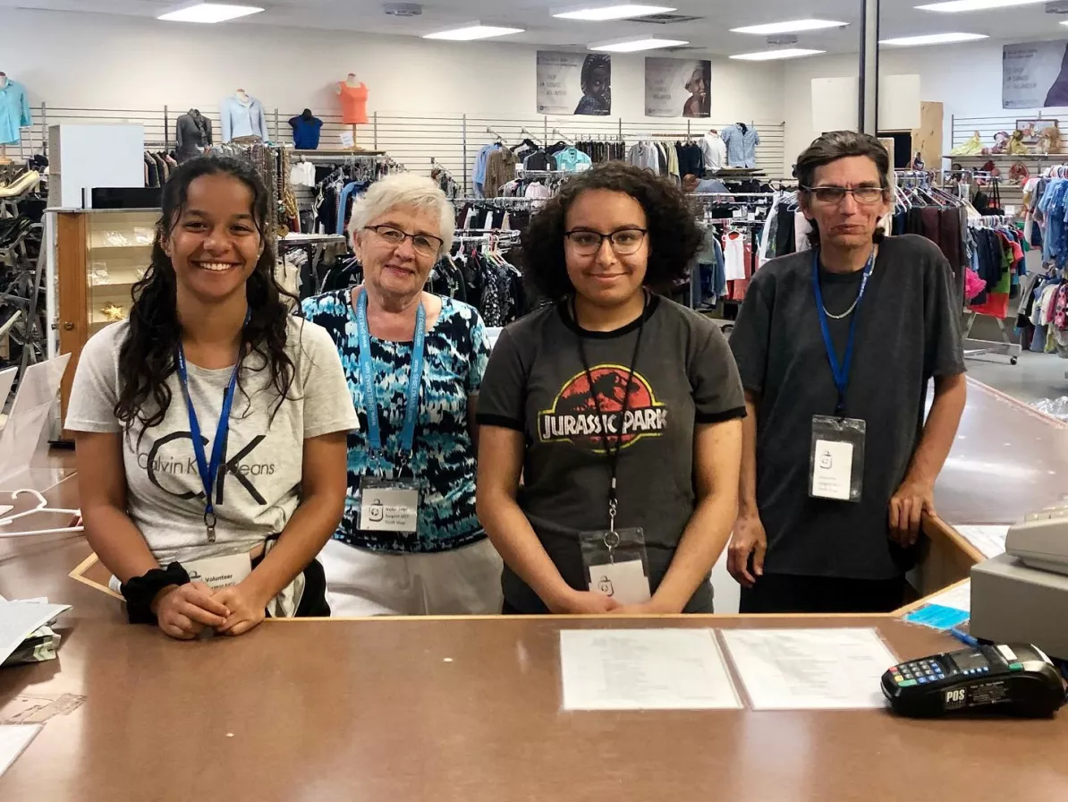 Four people stand behind a cash counter at a thrift shop