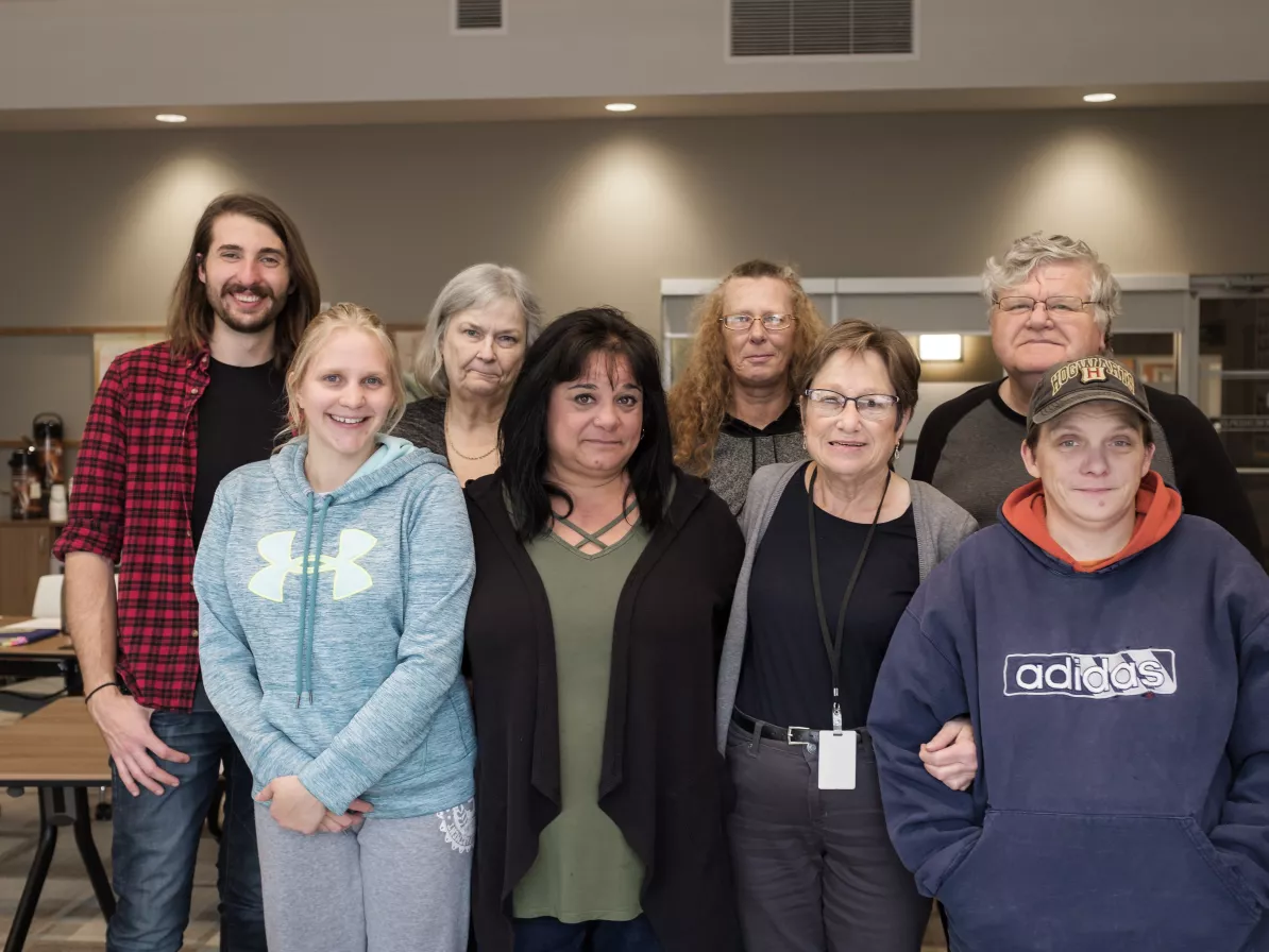 Eight people stand in two rows to take a group photo