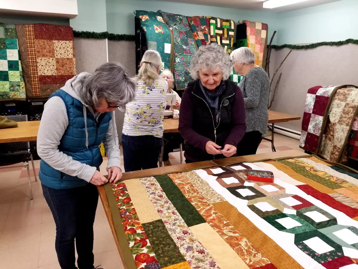 Two women sewing a comforter