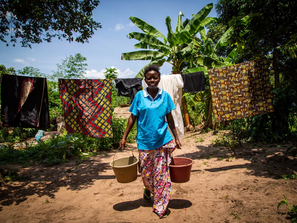 A young girl holding two buckets of water