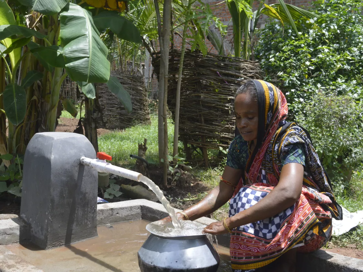 A woman pumping water from a water pump