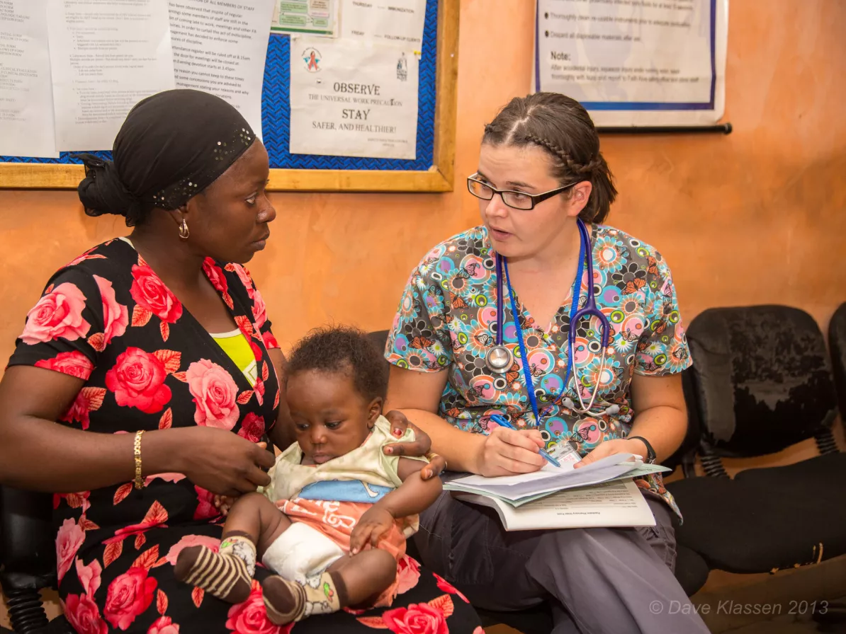 A woman talking to a mother holding her child