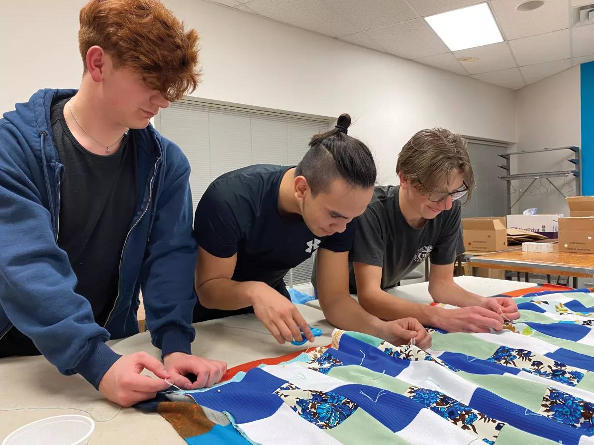 Three young men knotting a comforter