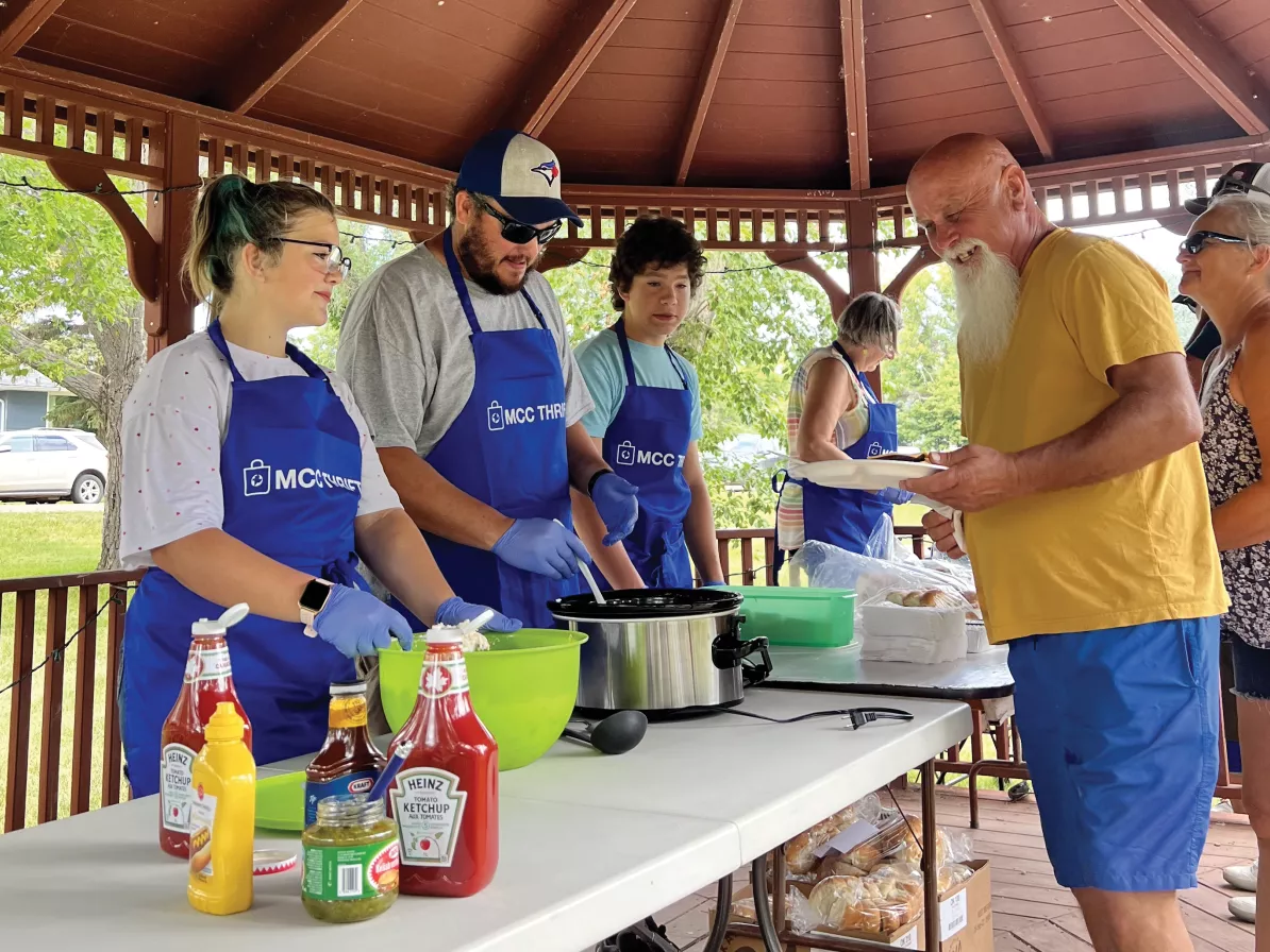 MCC Thrift workers serving food to a line of people