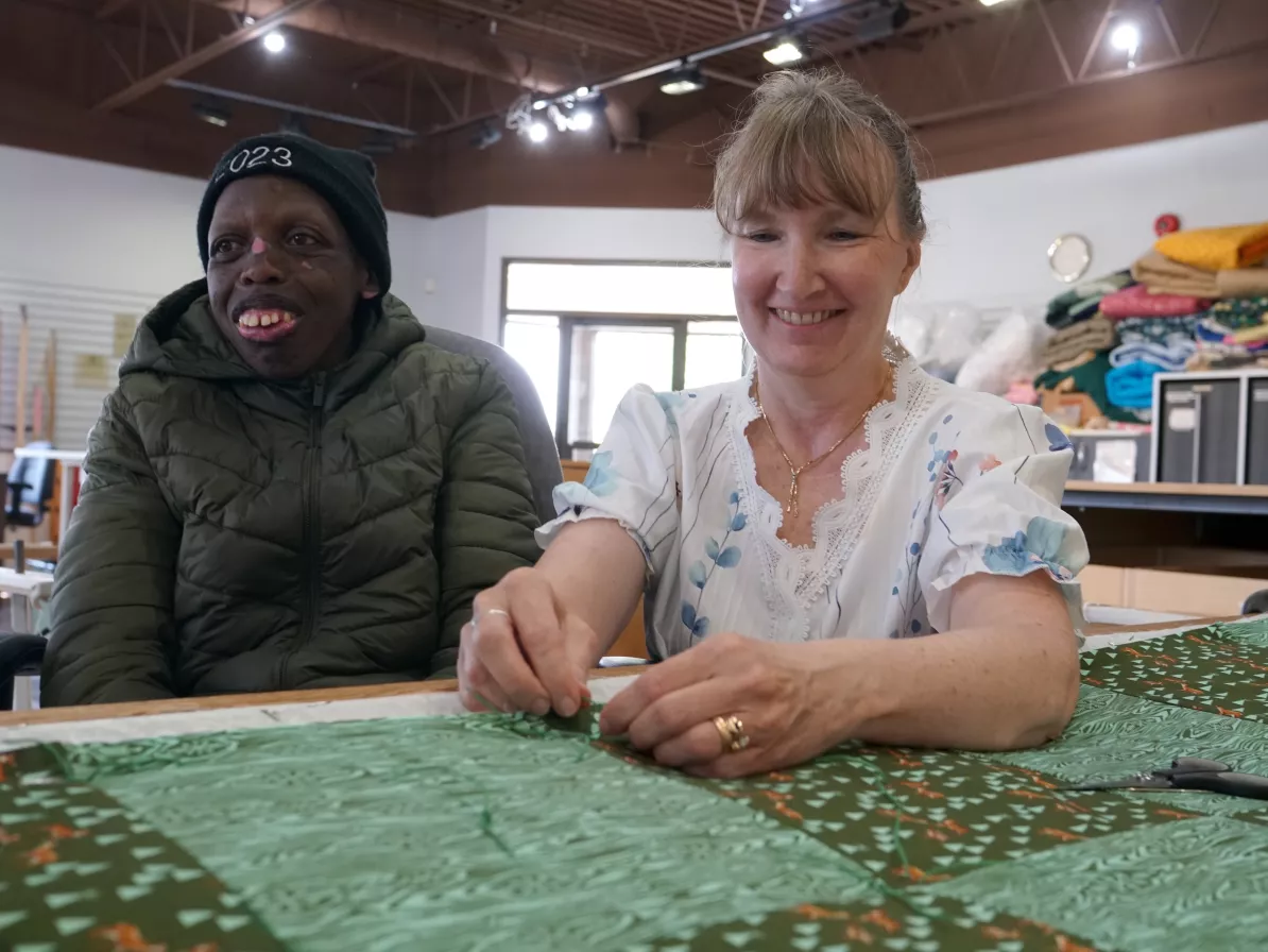 Two women sitting in front of MCC comforter