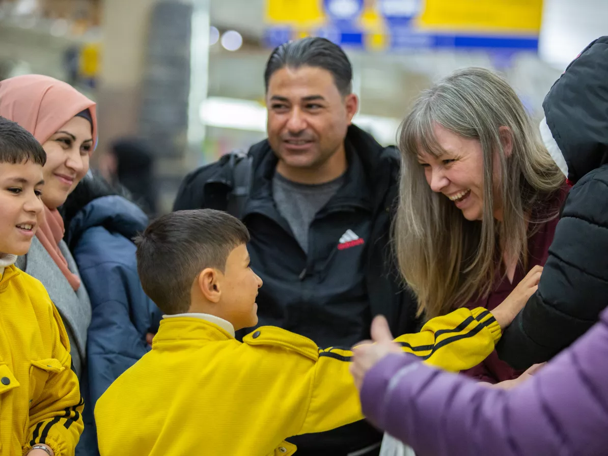 a family of refugees is greeted at the airport by their sponsors