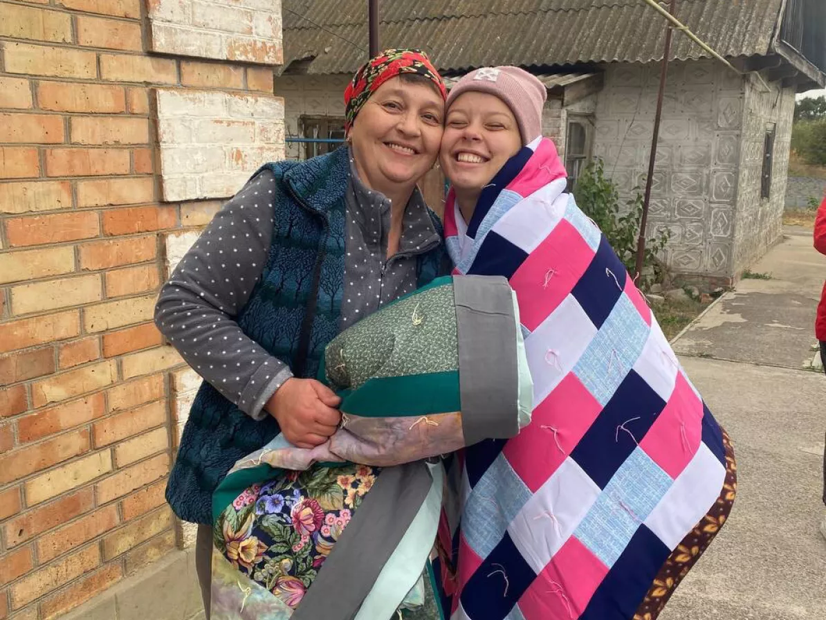 Two women receive MCC comforters in the Zaporizhzhia region of Ukraine