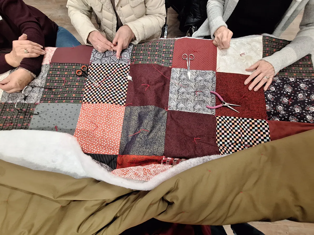 Several sets of hands tying blankets to be sent internationally