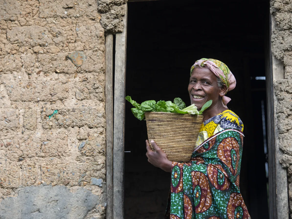Esperence Bagirinka displays amaranth greens grown in her kitchen garden using skills learned through her farmer field school. Since establishing a kitchen garden at her home, Bagirankana has begun in