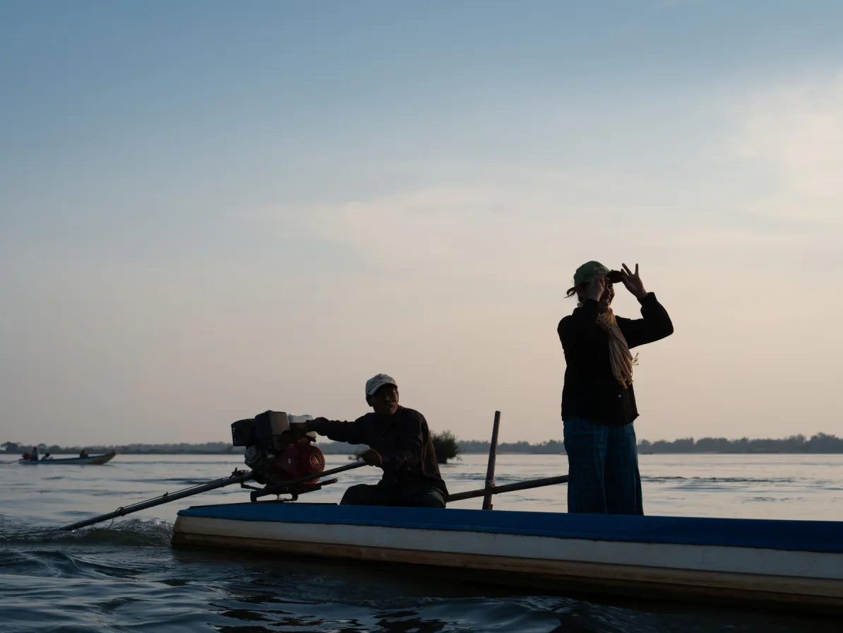 Theum Chan Thou, one of the women's group coordinators, stands in a boat  during a patrols in  the Mekong River.