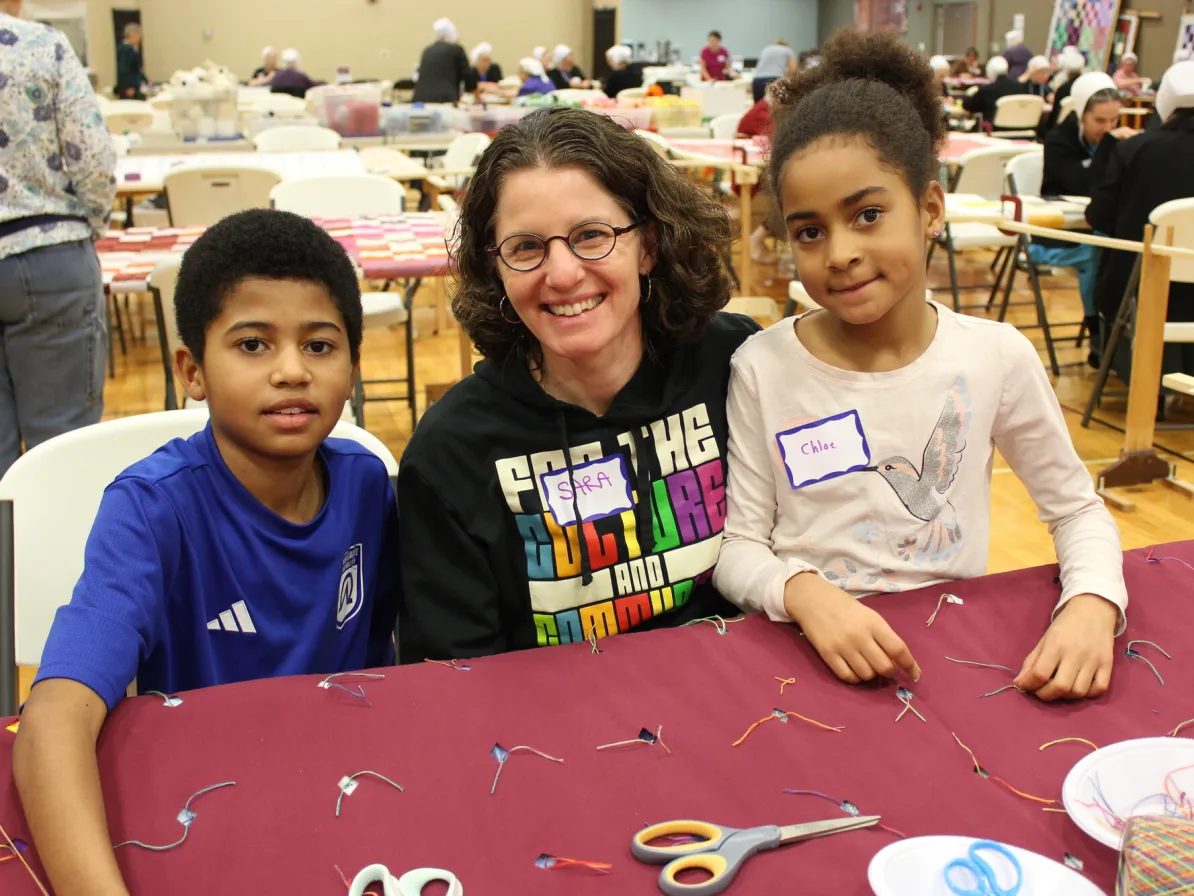 Sara Obri knots a comforter with her children, Isaac and Chloe, at the 2025 Ohio MCC Comforter Bash.