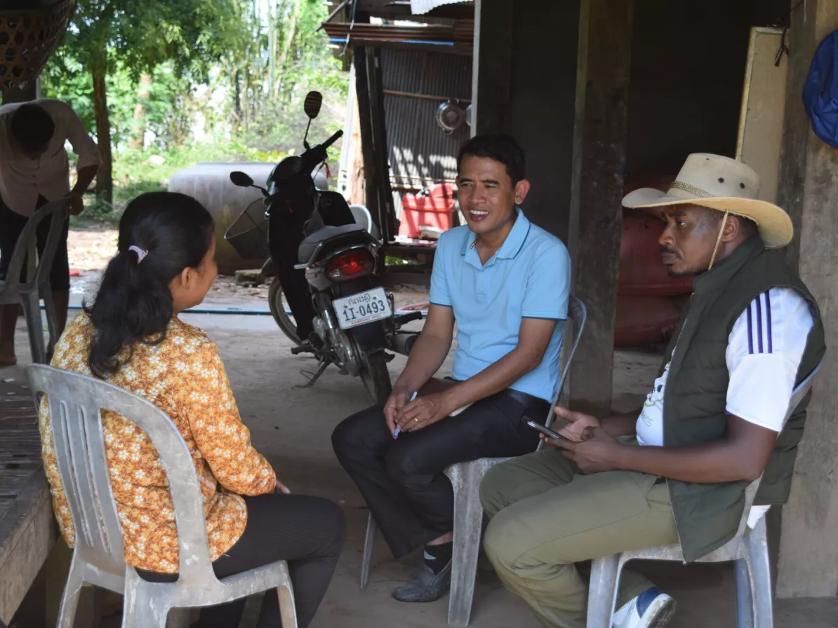 MCC Cambodia staff Aim Mok (middle) and Victor Odinda (right) have a lively chat and exchange ideas with Chroun Sophat (left), a disabled farmer, during a project monitoring visit. Sophat explained ho