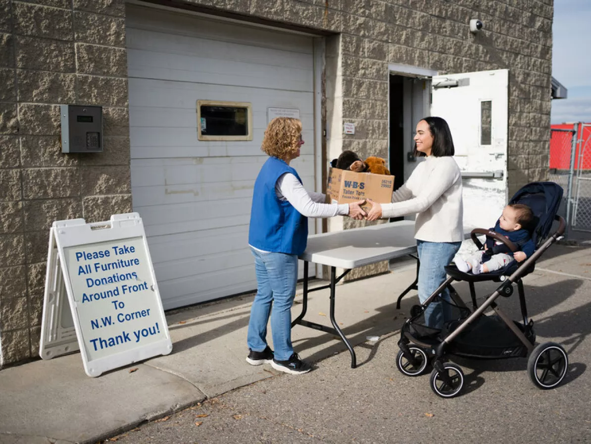 Calgary MCC Thrift Shop volunteer, Trudy Leiding accepts a donation of stuffed animals from Marcela Morales and her son Santiago Barahona.